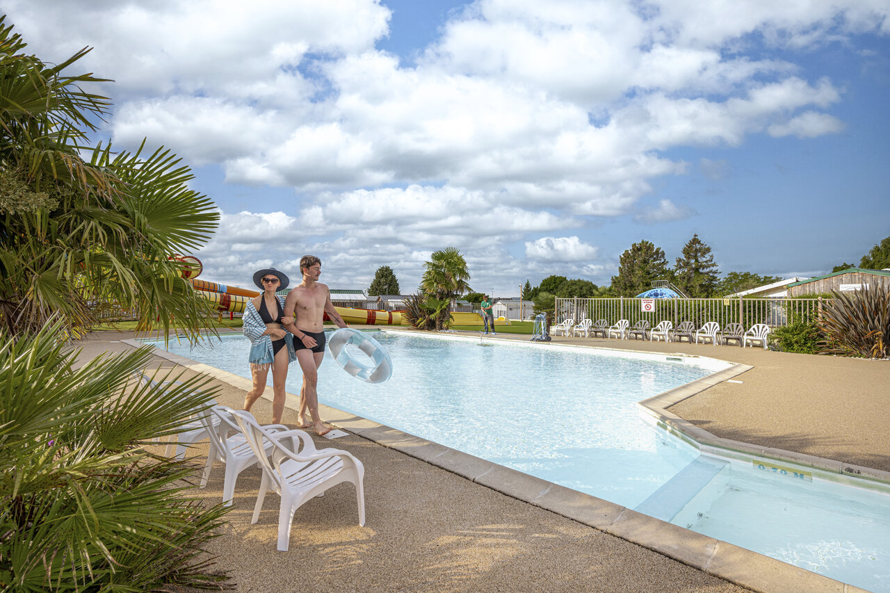 Paar am Au�enpool mit Rutschen auf Campingplatz CLICOCHIC Haras de Deauville.