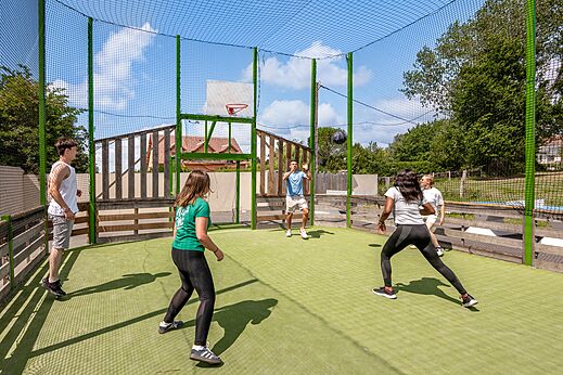 Jugendliche spielen Basketball auf Multisportplatz auf dem Campingplatz CLICOCHIC Haras de Deauville.