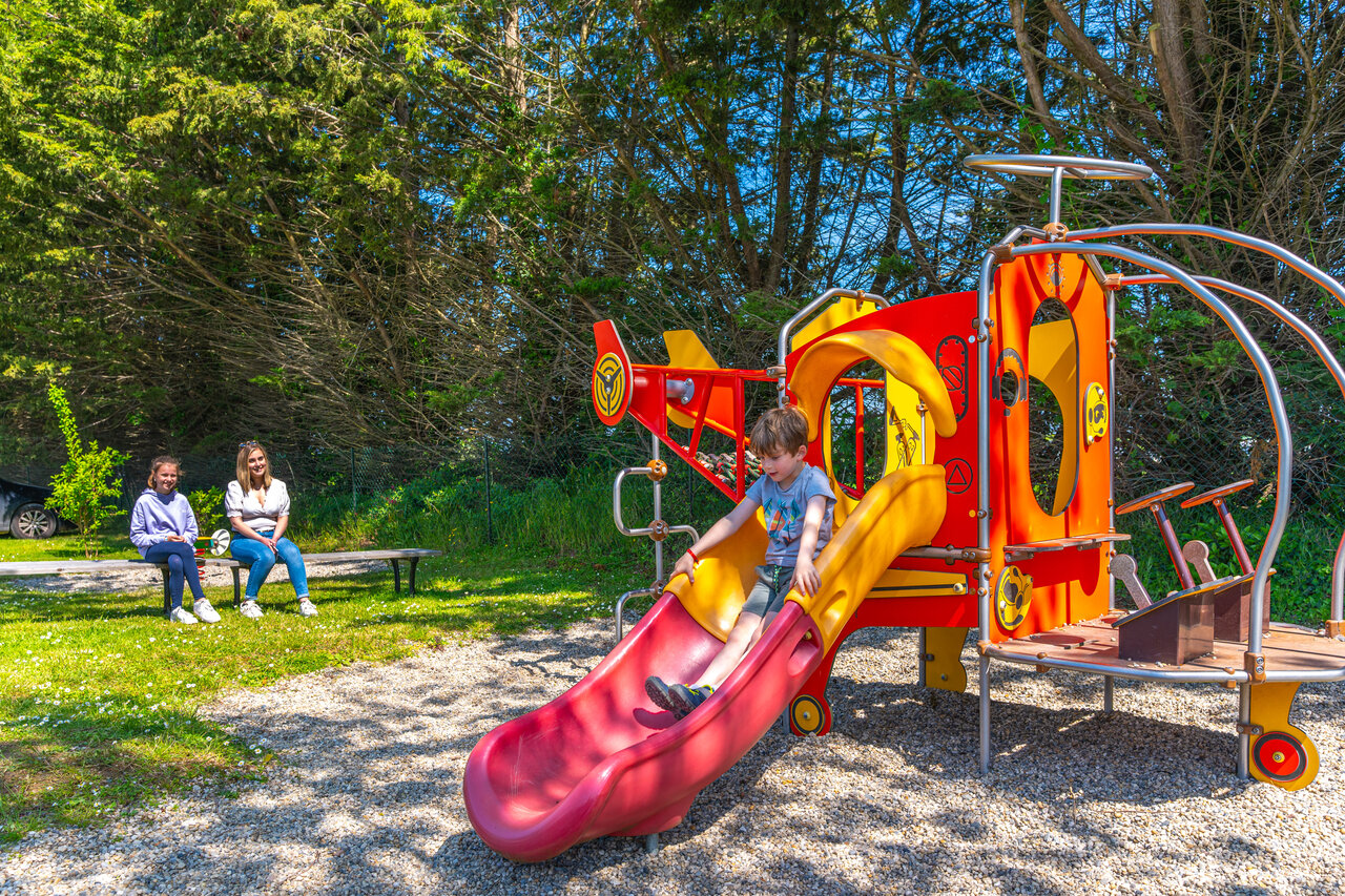 Kind auf bunter Rutsche des Spielplatzes auf dem Campingplatz CAPFUN Hautes Coutures in BENOUVILLE (14).