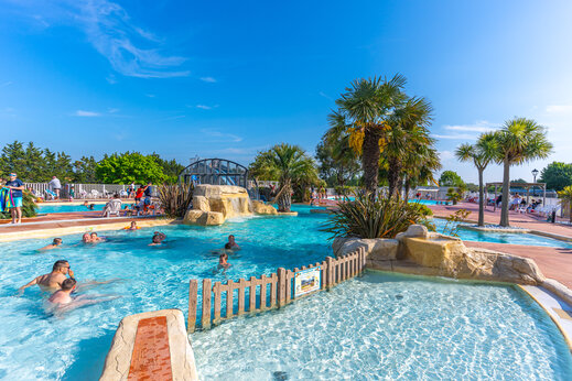 Buitenzwembad, waterval en palmbomen op camping CAPFUN Hautes Coutures in BENOUVILLE (14).