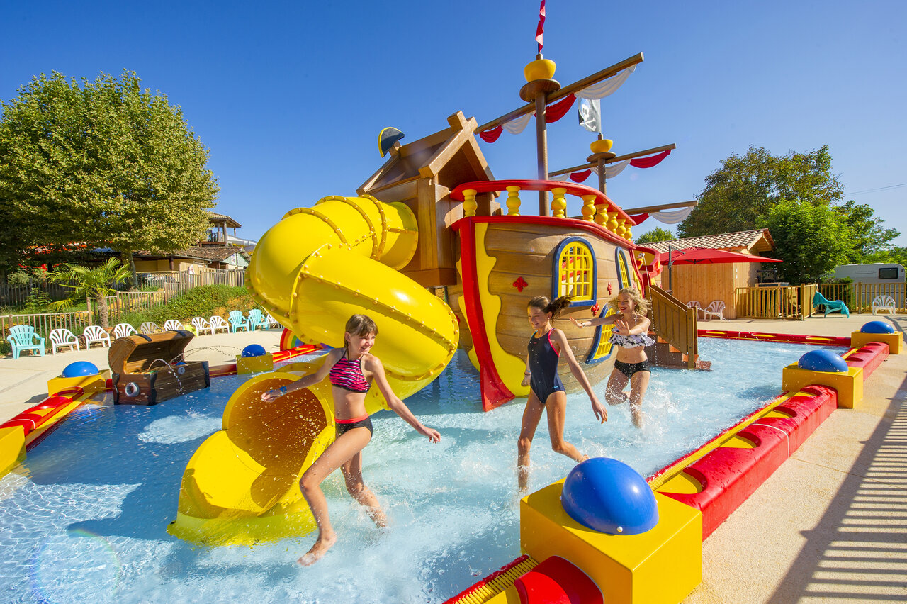 Pirate ship water play area, yellow slide, children at CAPFUN Hauts de Ratebout campsite in STE FOY DE BELVES (24).