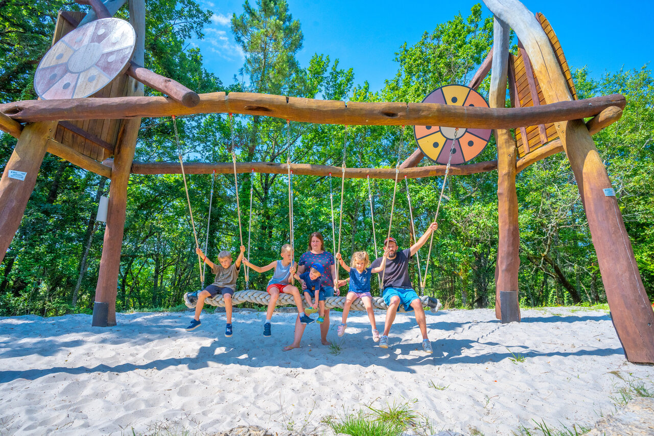 Family enjoying giant swing on sand at CAPFUN Hauts de Ratebout campsite in STE FOY DE BELVES (24).
