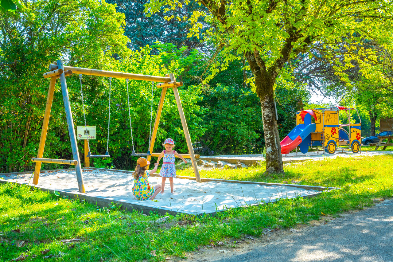 Playground, swing set, and slide for children at CAPFUN Hauts de Ratebout campsite.