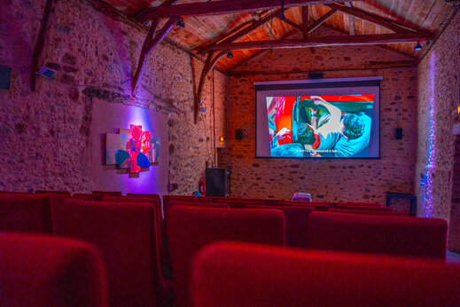 Innenkino mit Projektionsleinwand und roten Sitzen auf dem Campingplatz CAPFUN Hauts de Ratebout in STE FOY DE BELVES (24).
