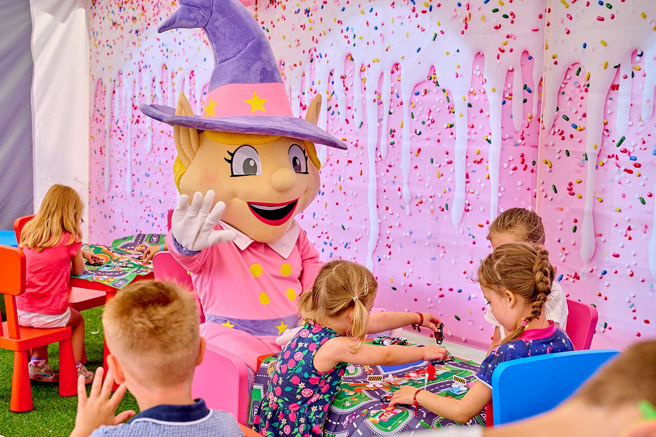 Maskottchen und Kinder spielen Brettspiele auf dem Campingplatz CAPFUN Heino in Heino.