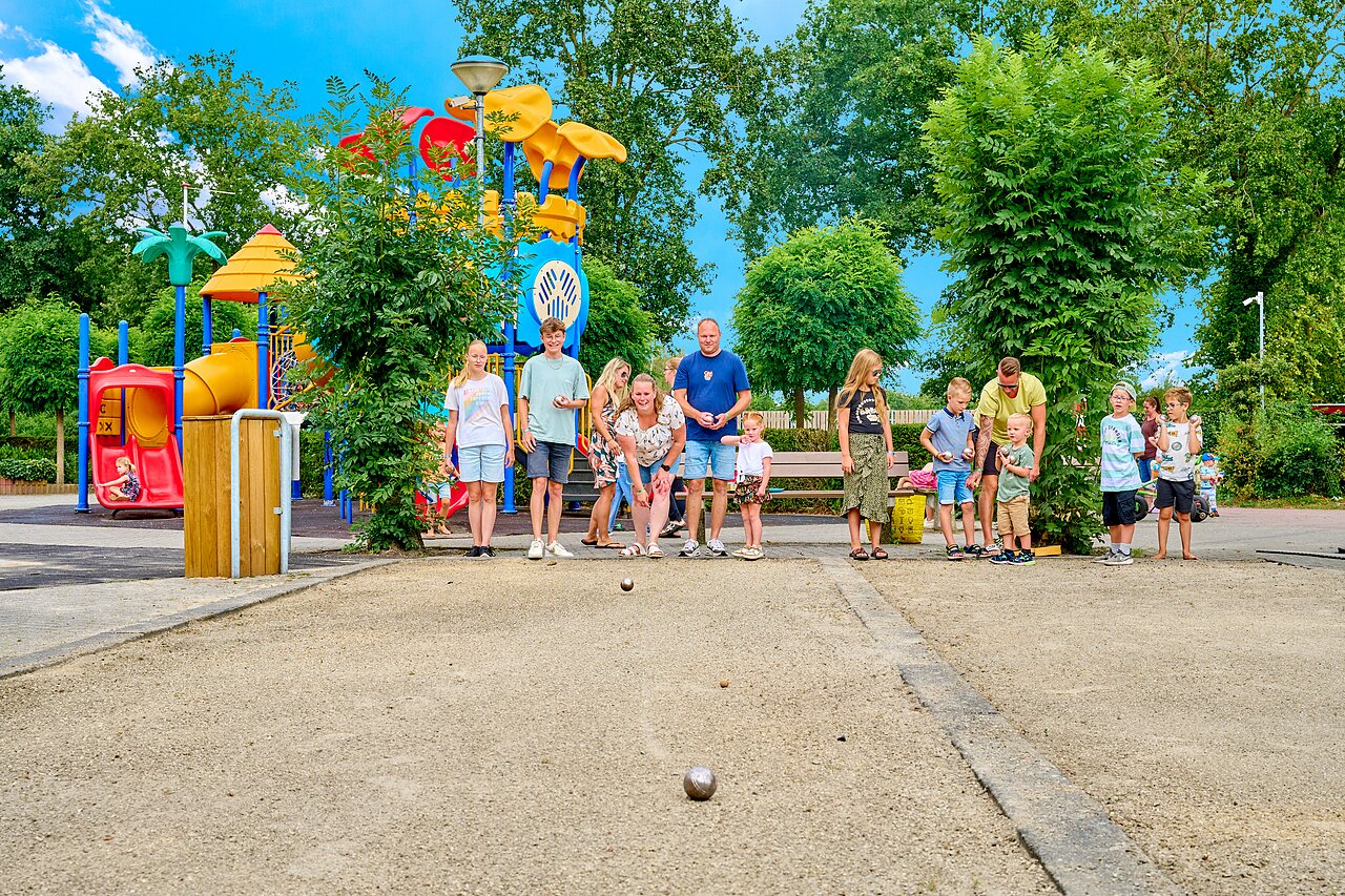 Familie spielt Boule neben Spielplatz auf dem Campingplatz CAPFUN Heino in Heino.