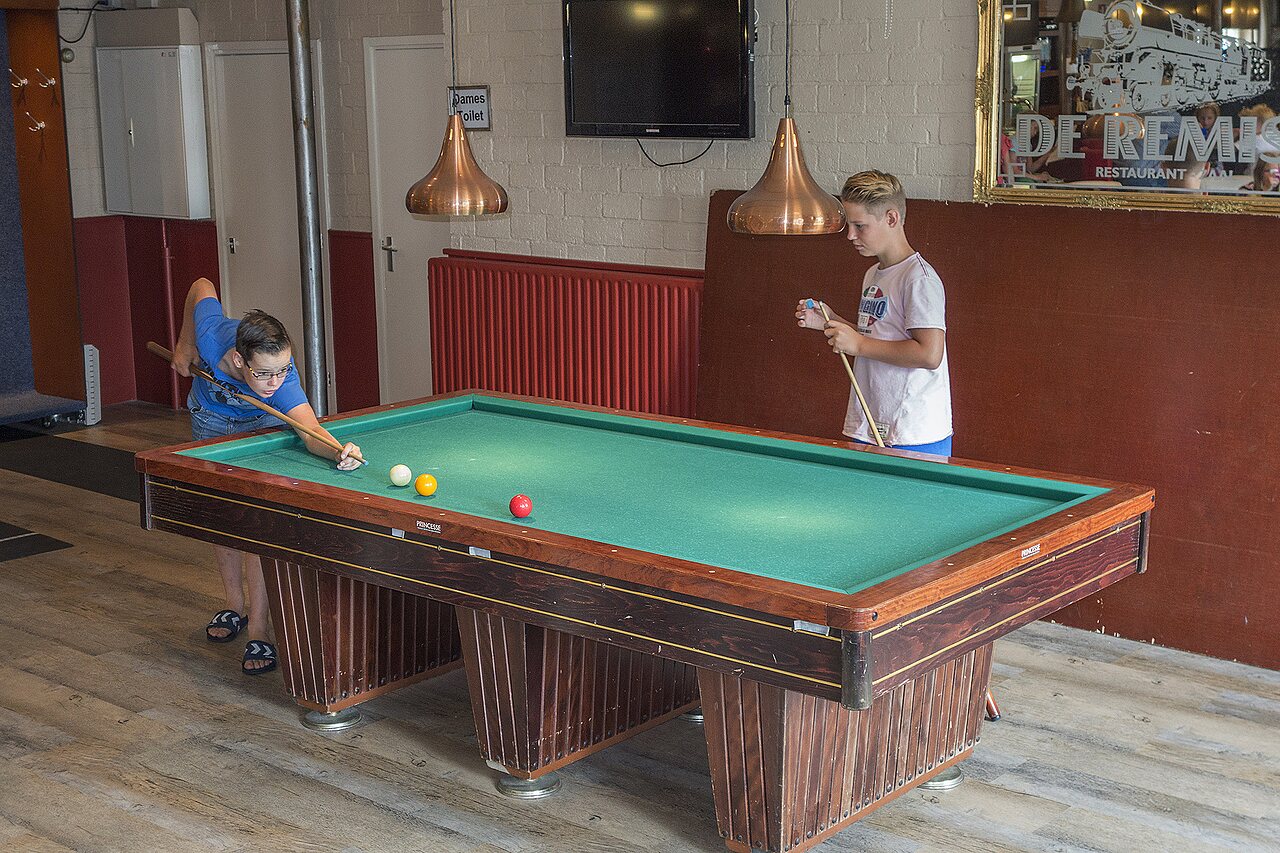 Kinder spielen Billard im Spielbereich des Campingplatzes CAPFUN Heino in Heino.