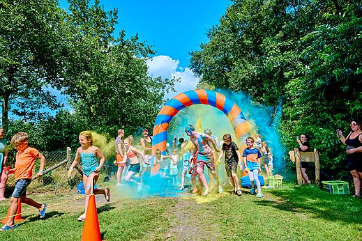 Kinder und Erwachsene bei Farblauf unter aufblasbarem Bogen auf Camping CAPFUN Heino in Heino.
