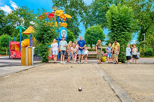 Familie spielt Boule neben einem Spielplatz auf dem Campingplatz CAPFUN Heino in Heino.