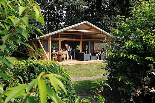 Modernes Lodge-Zelt mit Terrasse und Familie auf dem Campingplatz CAPFUN Heino in Heino.