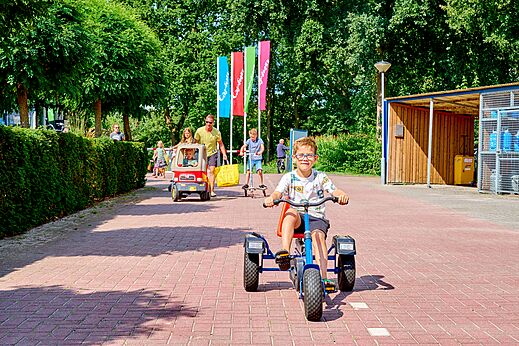 Kinder spielen mit Tret-Gokart, Spielzeugauto und Roller auf Camping CAPFUN Heino in Heino.