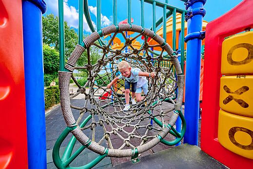 Child in rope tunnel on playground at CAPFUN Heino campsite.