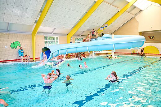 Hallenbad mit Wasserrutsche und Badegästen auf dem Campingplatz CAPFUN Heino in Heino.