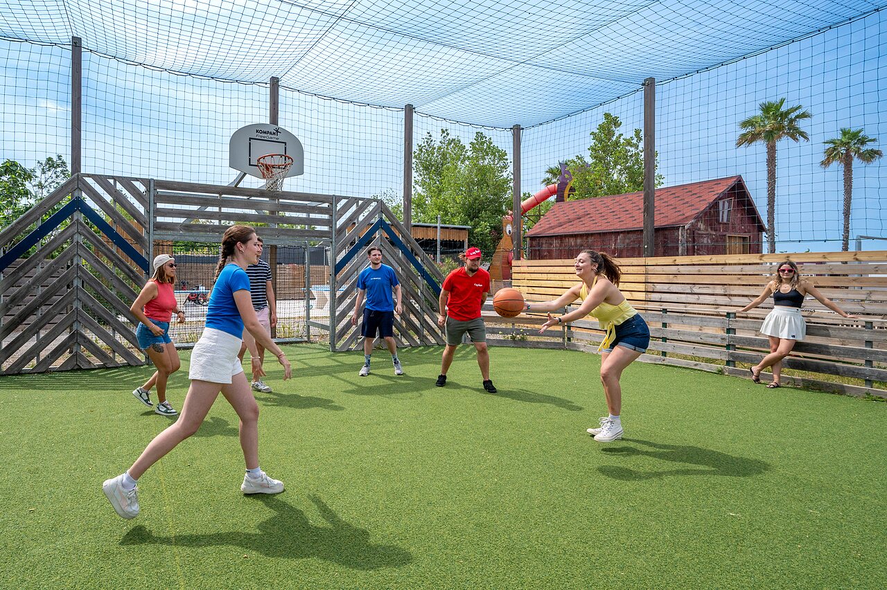 Multisport court with young people playing basketball at CAPFUN Hermitage campsite in SERIGNAN (34).