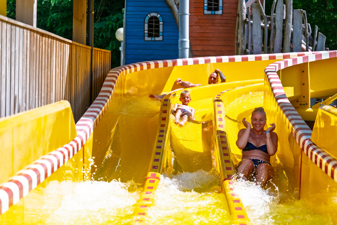 Familie hat Spa� auf der gelben Wasserrutsche auf dem Campingplatz CAPFUN Hirondelle in Oteppe.