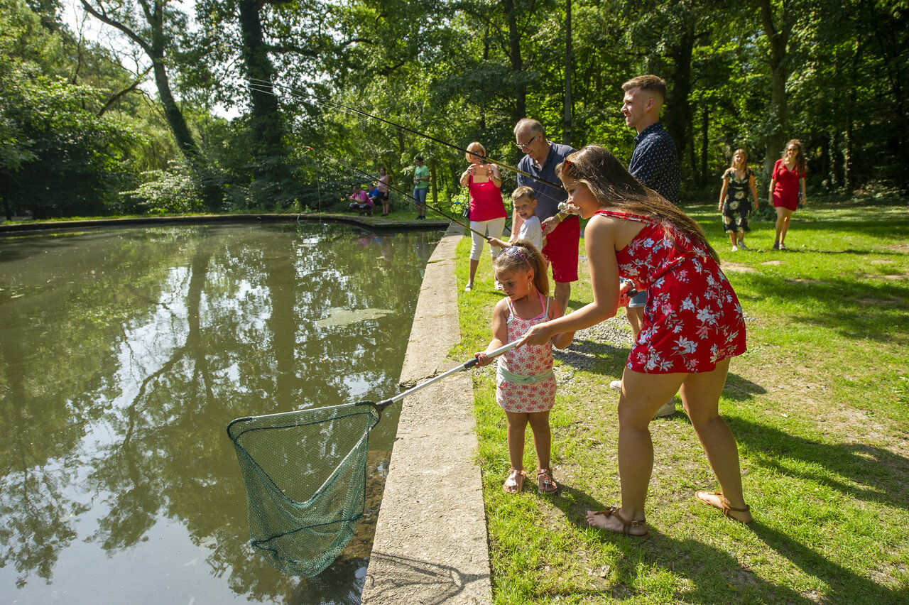 Familie angelt mit Kescher am Teichufer auf dem Campingplatz CAPFUN Hirondelle in Oteppe.