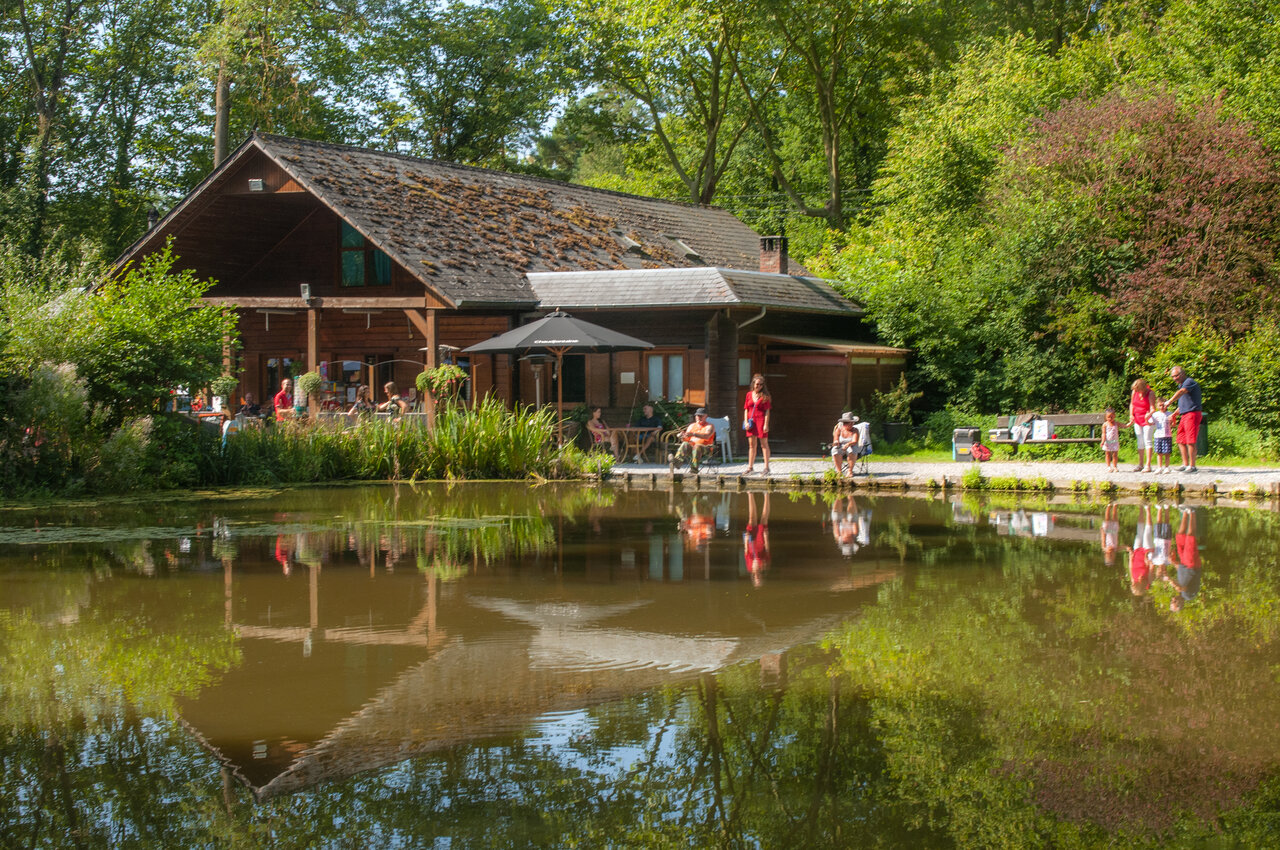Restaurantgeb�ude mit Terrasse am Teich, Angler auf dem Campingplatz CAPFUN Hirondelle in Oteppe.