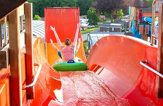 Person auf Reifen rutscht große Wasserrutsche hinunter auf Camping CAPFUN Hirondelle in Oteppe.