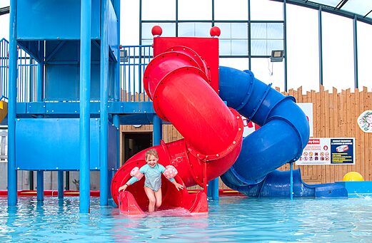 Wasserrutsche und Schwimmbad mit lachendem Kind im CAPFUN Hirondelle Camping Oteppe.