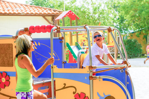 Lachendes Kind und Frau auf Spielplatz auf dem Campingplatz CAPFUN Huttes in Saint-Denis d'Oléron.