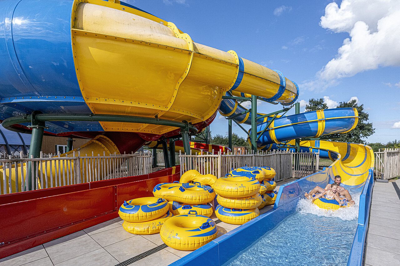 Riesige Wasserrutschen und Personen auf Reifen im CAPFUN IJsselstrand Camping in Doesburg.