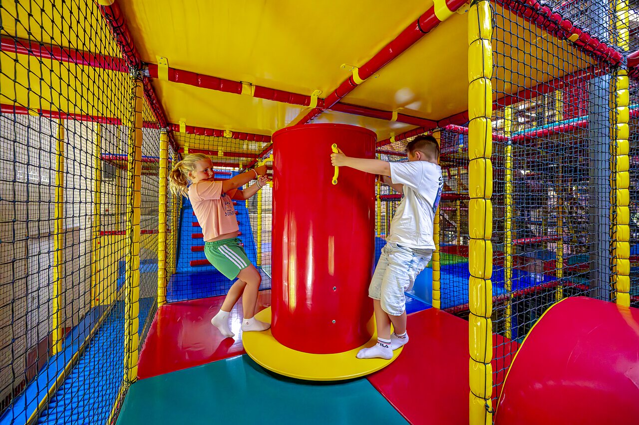 Kinder spielen in einer farbenfrohen Indoor-Spielstruktur auf dem Campingplatz CAPFUN IJsselstrand in Doesburg.