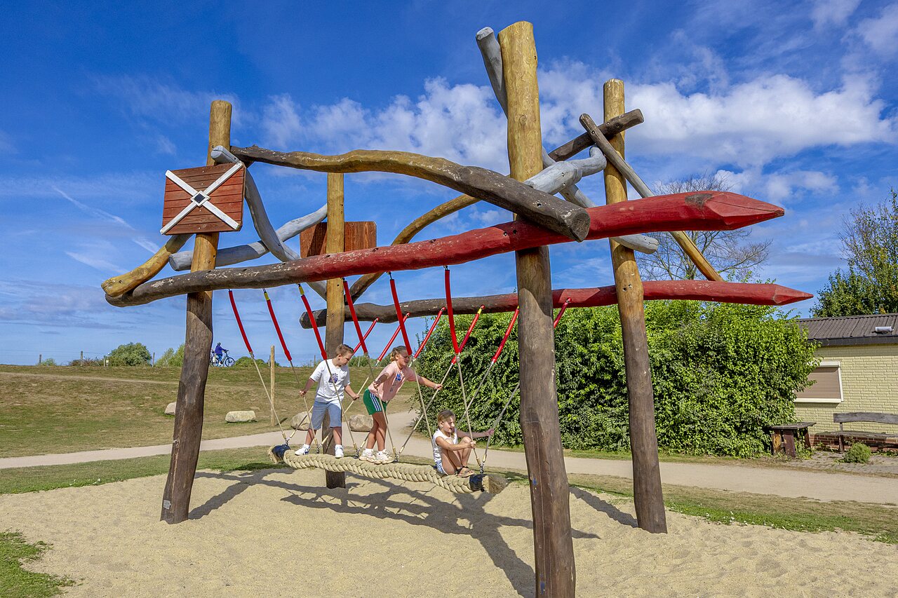 Kinder spielen auf Holz- und Seilspielplatzstruktur auf Camping CAPFUN IJsselstrand in Doesburg.