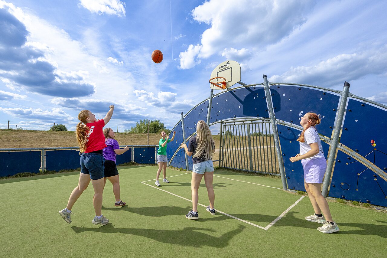 Jugendliche spielen Basketball auf einem Multisportplatz im Camping CAPFUN IJsselstrand in Doesburg.