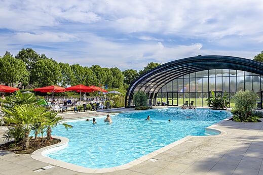 Outdoor and indoor swimming pool with bathers at CAPFUN IJsselstrand campsite in Doesburg.