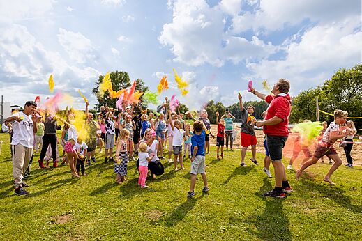Kinder und Erwachsene bei einer Farbpulver-Animation auf dem Campingplatz CAPFUN IJsselstrand in Doesburg.