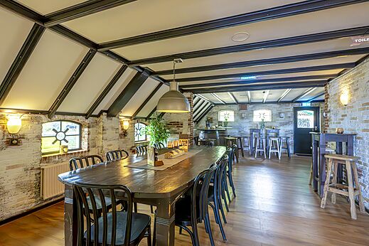 Restaurant und Bar mit langem Holztisch und Ziegelw�nden auf dem Campingplatz CAPFUN IJsselstrand in Doesburg.
