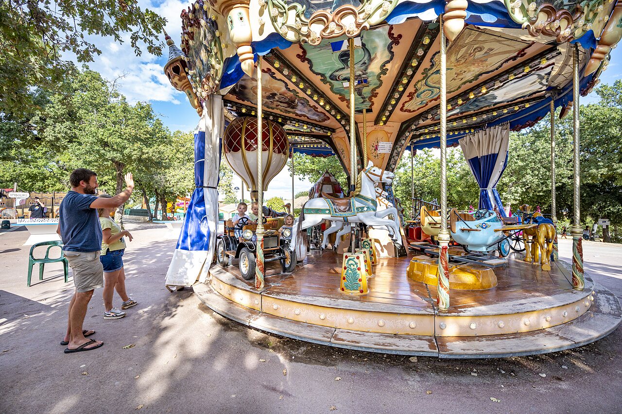 Kleurrijke draaimolen met lachende kinderen op camping CAPFUN Imbours in LARNAS (07).
