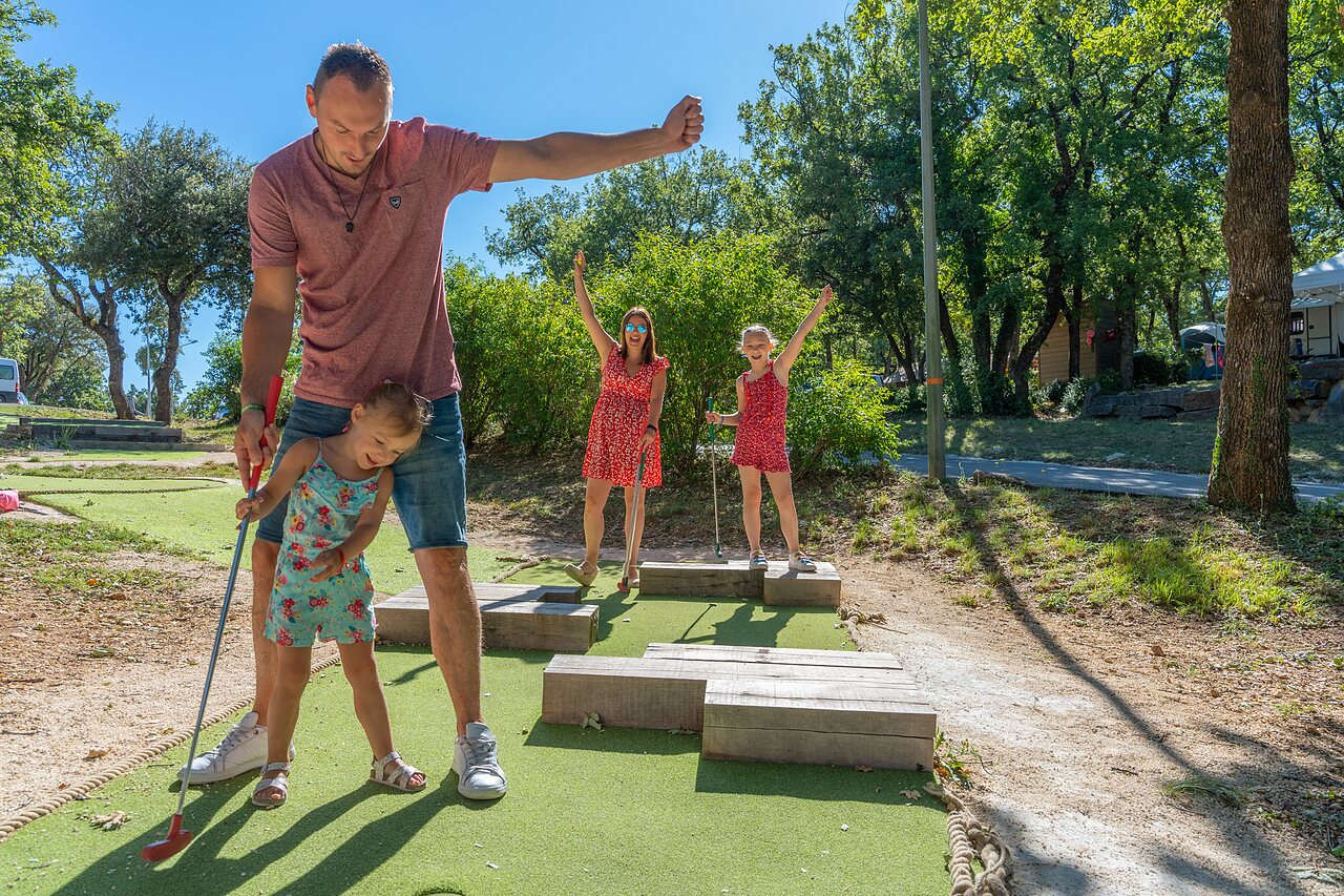 Familie speelt minigolf op buitenbaan op camping CAPFUN Imbours in LARNAS (07).