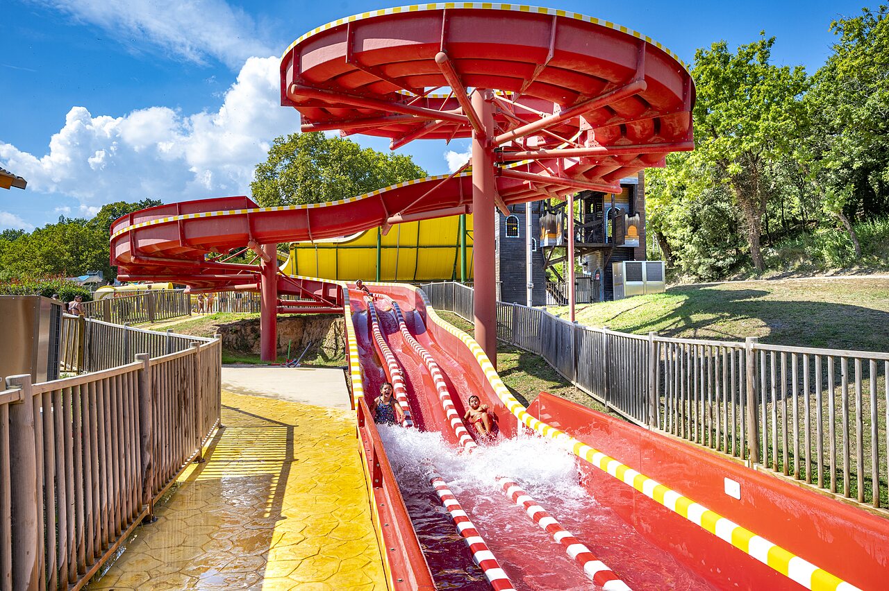 Grote rode waterglijbaan met kinderen op camping CAPFUN Imbours in LARNAS (07).