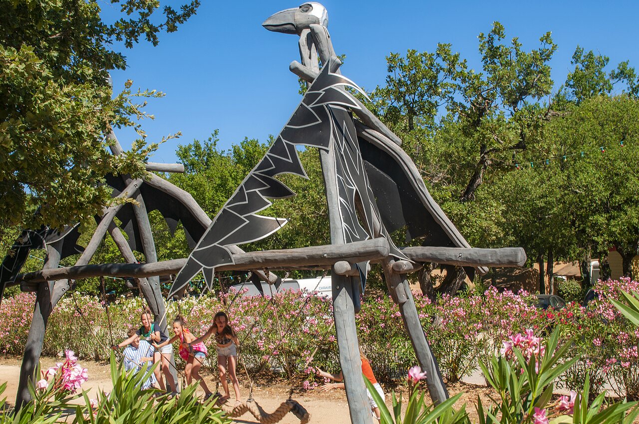 Draak speeltoestel met kinderen op schommels op camping CAPFUN Imbours in LARNAS (07).