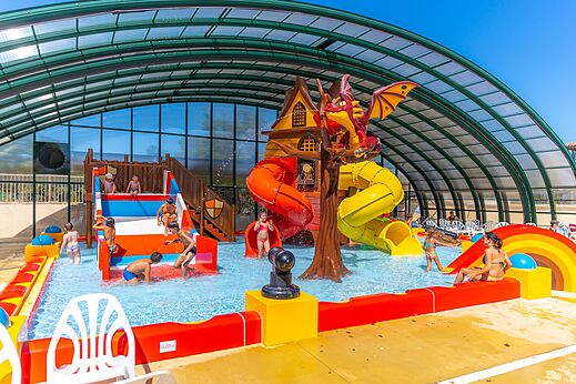 Überdachter Wasserspielplatz mit Rutschen und Drachen auf dem Campingplatz CAPFUN Imbours in LARNAS (07).