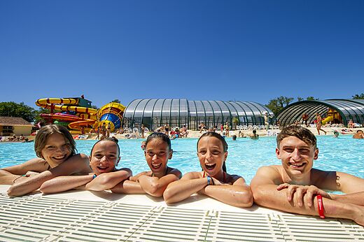 Lachende Familie im Schwimmbad mit Rutschen auf dem Campingplatz CAPFUN Imbours in LARNAS (07).