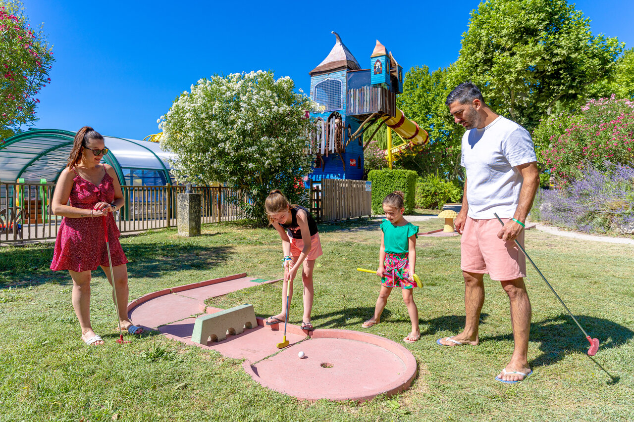 Familie spielt Minigolf mit Spielplatz und Pool auf dem Campingplatz CAPFUN Jantou in LE THOR (84).