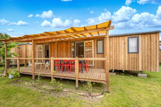 Holz-Mobilheim, überdachte Terrasse, rote Stühle, Camping CAPFUN Jantou (84).