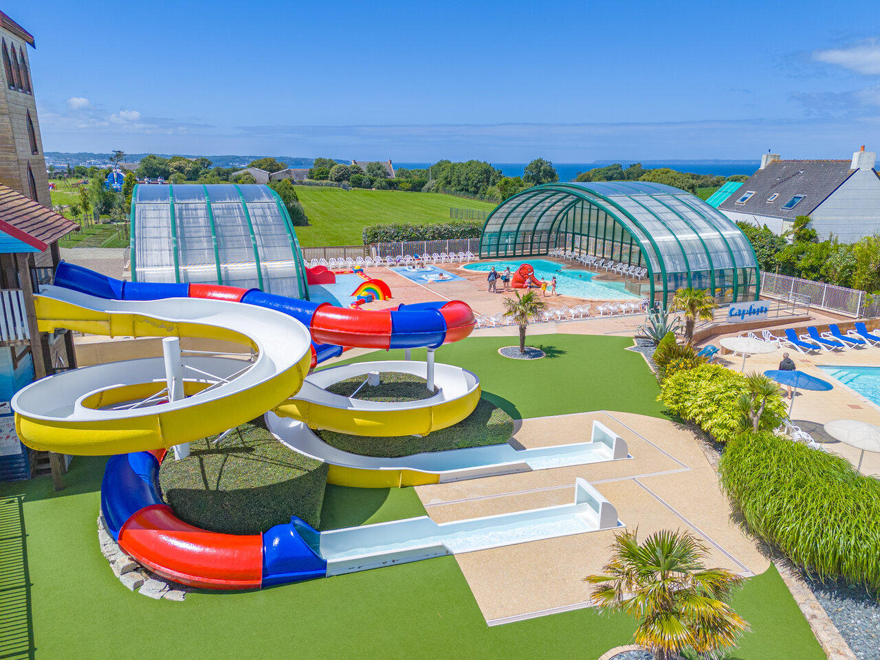 Kleurrijke waterglijbanen, buiten- en binnenzwembad op camping CAPFUN Kervel in PLONEVEZ PORZAY.