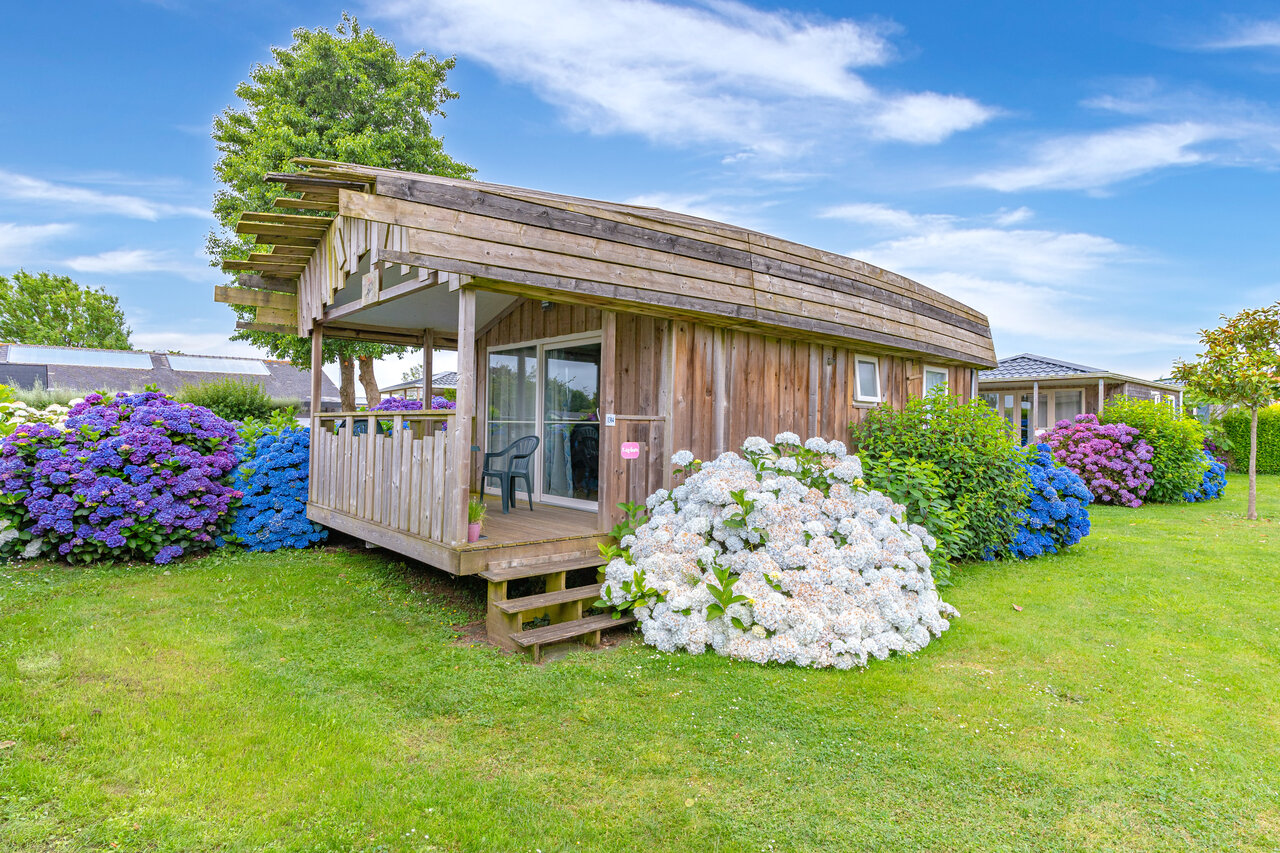Houten chalet met terras en kleurrijke hortensia's op camping CAPFUN Kervel in PLONEVEZ PORZAY (29).