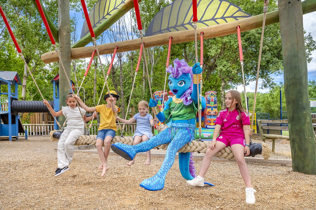 Enfants et mascotte sur une balan�oire g�ante au camping VAGUES OCEANES Labeiller � Saint Victor de Malcap (30).