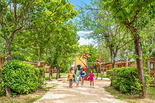 Farbenfroher Spielplatz mit Rutsche und schattigen Mobilheimen auf dem Campingplatz VAGUES OCEANES Labeiller in Saint Victor de Malcap.