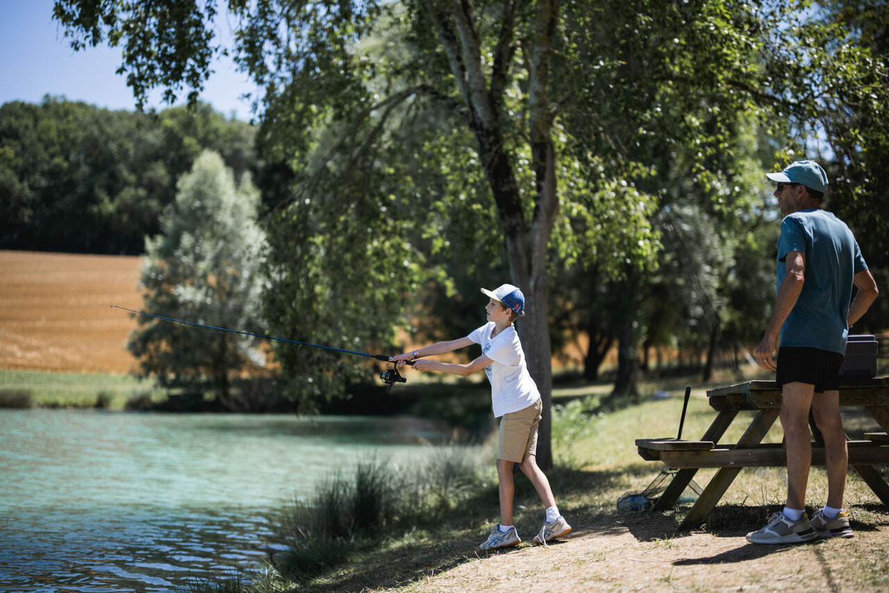 Kind angelt am See mit einem Erwachsenen auf dem Campingplatz CAPFUN Lac des 3 Vall�es.