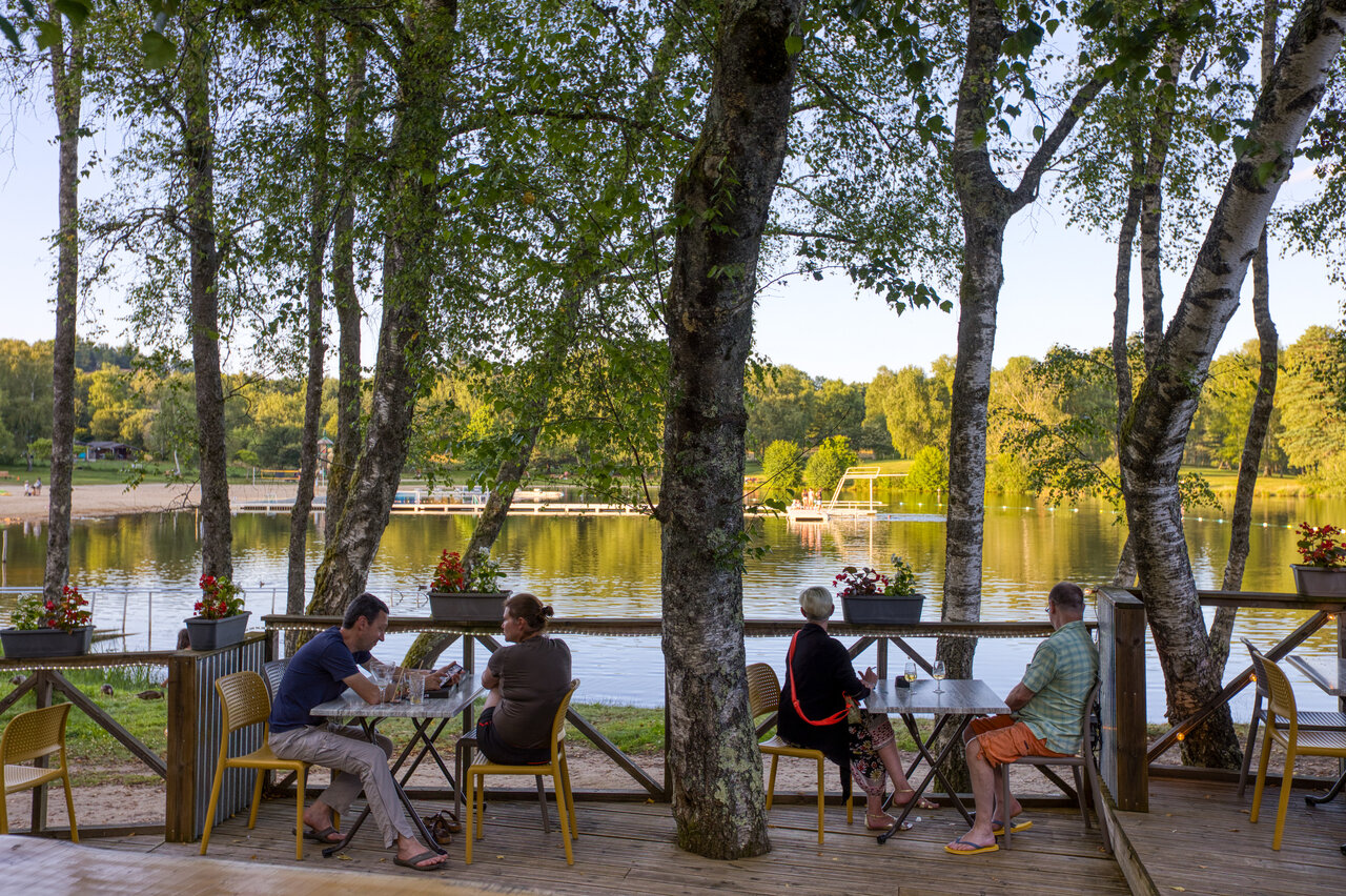 Terraza de restaurante sombreada, lago, playa en el camping CLICOCHIC Lac de Miel.