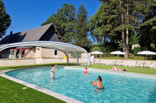 Zwembad met overkapping, familie speelt bal op camping CLICOCHIC Lac de Miel.