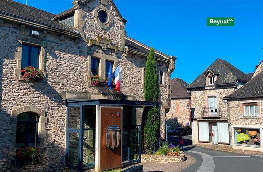 Stadhuis van Beynat, stenen gebouw met Franse vlaggen, Corrèze.