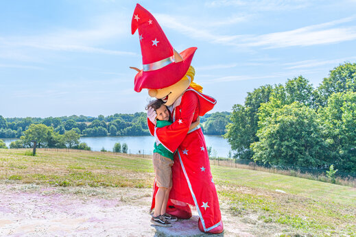 Enfant souriant �treignant la mascotte du camping lors d'une animation au camping CAPFUN Lac de Ribou � Cholet (49).