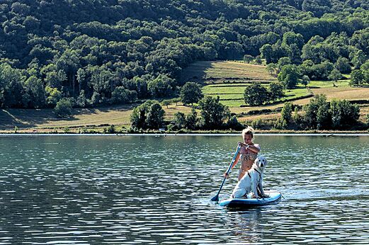 Stand-up Paddle mit Hund auf dem See auf dem Campingplatz CLICOCHIC Lac du Lit du Roi in Massignieu-de-Rives (01).