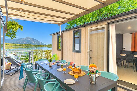 Mobilheim mit Terrasse, Tisch, Stühlen, Seeblick auf dem Campingplatz CLICOCHIC Lac du Lit du Roi in Massignieu-de-Rives (01).